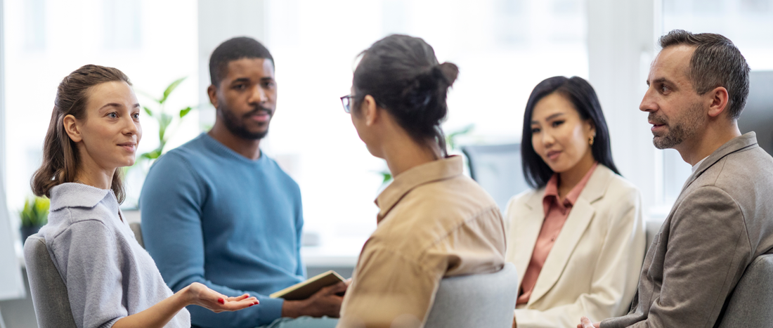 "A diverse group of individuals participating in a supportive group therapy session, highlighting the benefits of peer support and social connection in mental health treatment."