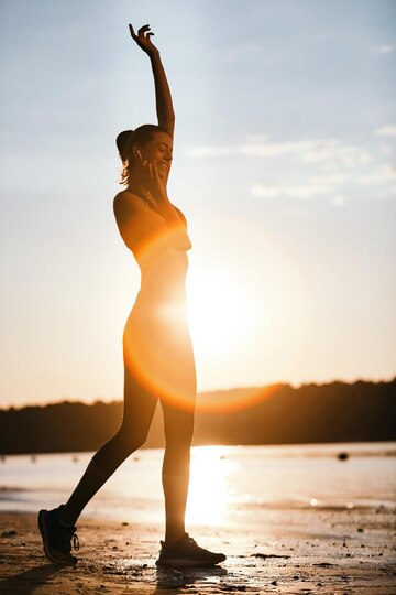 Boost your energy levels: Person stretching and smiling with renewed vitality, surrounded by bright sunlight and natural elements.